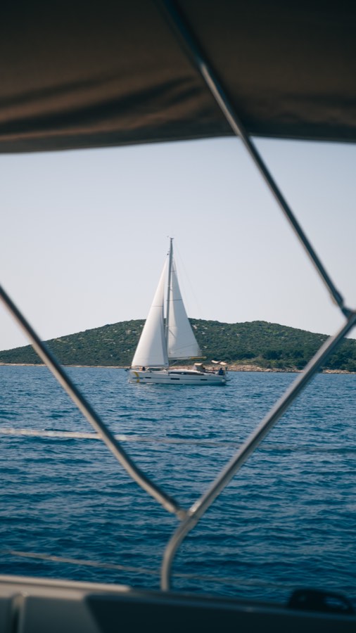 Sailboat framed by the cockpit of another boat